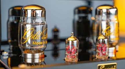 Primo piano di valvole termoioniche in vetro con basi metalliche, un grande tubo con scritte dorate e due piccoli contrassegnati in rosso