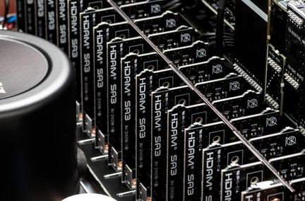 Įstrižas stambus planas, kuriame matomos kelios vertikaliai išdėstytos juodos kompozitinės elektroninės plokštės su balta šilkografija „HDAM SA3“ ir metaliniais jungtimis, išrikiuotos viduje važiuoklės, kairėje pusėje matomas didelis juodas metalinis cilindras