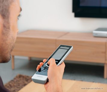 Philips SRU9600 grå og sort universal fjernbetjening, set forfra i nærbillede, holdt i en hånd på et træbord