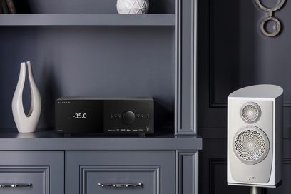 Anthem AVM 90 8K black home theater preamp, front view, with white bookshelf speaker on the right