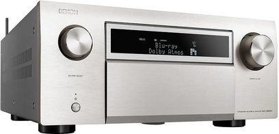 Denon AVC-X8500HA sidabrinės spalvos namų kino stiprintuvas, priekinis vaizdas, mėlynas ekranas rodo "Blu-ray Dolby Atmos", matomos mygtukai ir lizdai