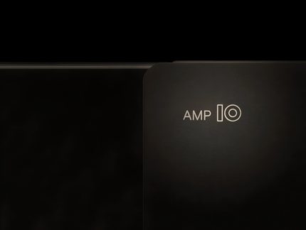 Primer plano frontal de un panel de metal negro mate con la inscripción 'AMP IO', borde redondeado a la derecha