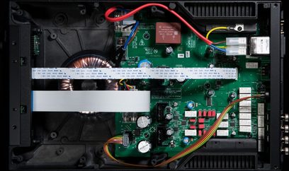 Cyrus Phono Signature fonografinio stiprintuvo vidinis vaizdas, rodantis žalias spausdintines plokštes su elektroniniais komponentais ir spalvotais laidais