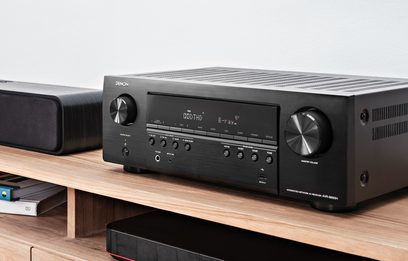 Denon AVR-S650H sort hjemmebiografsforstærker, set forfra, placeret på en lys træhylde, sort front med knapper og skærm