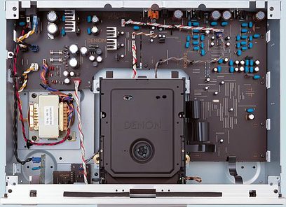 Widok wewnętrzny zdemontowanego odtwarzacza CD Denon DCD-1500AE, ukazujący złożone podzespoły elektroniczne i mechaniczne