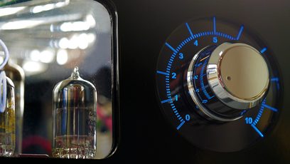 AudioValve Assistent 50 black hi-fi stereo amplifier, front view, chrome rotary knobs, vacuum tubes, glowing blue dial