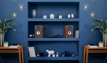 Blaue Regale mit Holz-Lautsprecherboxen, Plattenspieler, Kerzen und Eisbär-Figur, Vorderansicht