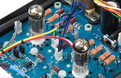 Modrá tištěná deska s různými elektronickými součástkami, elektronkami a barevnými kabely, detailní pohled do vnitřku elektronického zařízení
