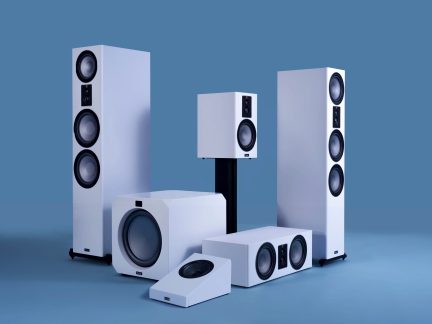 Set van 6 witte luidsprekers bestaande uit zuilen, subwoofer, center, surround en boekenplank op een effen blauwe achtergrond