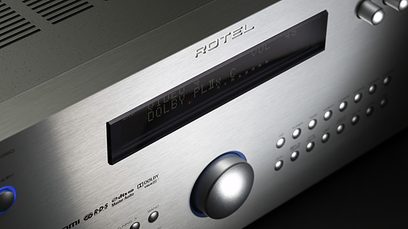 Černý domácí kino zesilovač Rotel RSX-1560. Detailní pohled na přední panel. Modrý displej, stříbrná tlačítka a ovládací kolečko