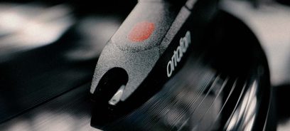 Pro-Ject E1 BT sort lakeret pladespiller, nærbillede af tonearmen med rød pickup, selektiv fokus