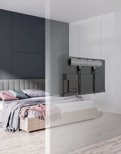 Gray wall-mounted TV stand with two TV mounts, in a bedroom with a bed and light gray headboard