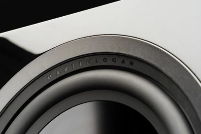 MartinLogan Dynamo 12 subwoofer, nærbillede af en sort, cirkulær højttaler med grå kant og synlig inskription