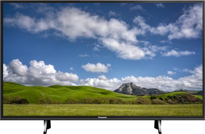 Panasonic TX-55FX600 tv der viser et landskab med grønne bakker og en skyet himmel, set forfra på et stativ