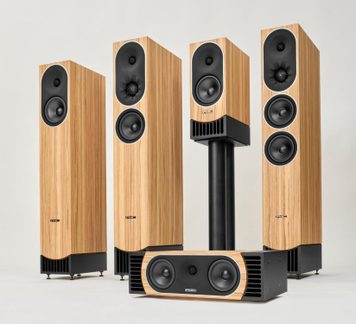 Set of PMC hi-fi speakers: floorstanding, stand-mounted bookshelf, and center speaker, light wood and black finish, front view