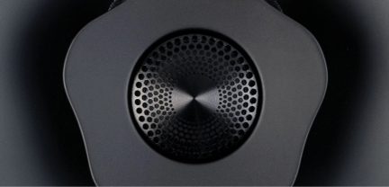 Vedere de aproape a unui difuzor negru circular cu o grilă perforată concentrică și un contur în formă de floare