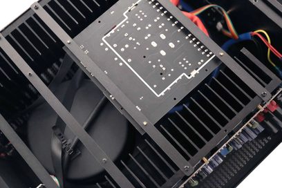 Ylhäältä otettu sisäkuva IOTAVX AVXP 2-840 -high fidelity -tehovahvistimesta: musta metallikotelo, kookas hihnalla varustettu toroidimuuntaja, suuri keskellä sijaitseva piirilevy ja molemmilla puolilla siivekkeelliset jäähdytysrivat.