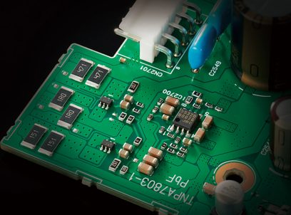 Placa de circuito impreso verde con componentes electrónicos de montaje superficial, incluyendo condensadores y resistencias