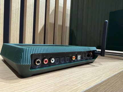 Case audio verde scuro vista posteriore, con antenna Wi‑Fi, porte RCA, ottiche, coassiale, USB, HDMI ARC e LAN