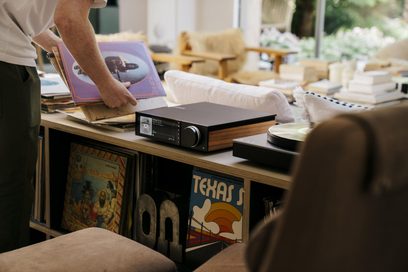 Amplificatore hi-fi integrato stereo Cambridge Audio EVO 150SE nero opaco, pannelli laterali in legno, grande schermo a colori a sinistra e manopola metallica a destra sul frontale, vista da tre quarti anteriore