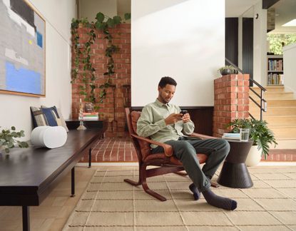 Cassa intelligente bianca su mobile TV in soggiorno moderno con uomo che usa il suo smartphone
