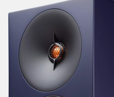 Tmavě modrý hi-fi reproduktor s koaxiálním šedým kuželovým měničem a centrálním oranžovým tweeterem s voštinovou mřížkou