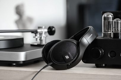 Ανοιχτά ακουστικά hi-fi Sennheiser HD 560S σε μαύρο χρώμα, σε πλάγια όψη, τοποθετημένα σε ασημένιο πικάπ με λυχνίες στο παρασκήνιο