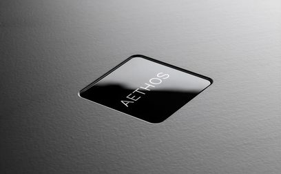 Rega Aethos stereoanlegg i sort, nærbilde ovenfra av frontpanelet i glass med hvit logo og teksten "AETHOS"