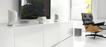 Interior minimalista moderno en blanco con sillón de cuero negro, altavoces blancos, pantalla de TV y gran ventanal