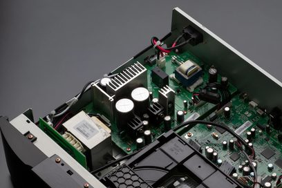 Vista interior de um leitor de CD Marantz CD6007 preto mostrando os componentes eletrônicos em uma placa de circuito impresso verde