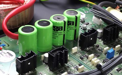 Close-up view of green capacitors aligned on a printed circuit board of a Rega Aura MC phono preamp, with wires and components
