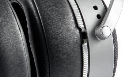 Close-up side view of the black faux leather earpad, the silver knurled ring, and the perforated aluminum hinge of the Audeze LCD-S20 headphones