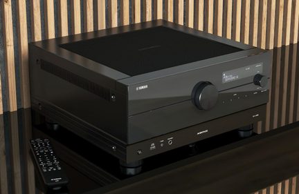AV receiver Yamaha Aventage RX-A8A čierny v trojštvrťovom pohľade spredu na lakovanom TV nábytku s diaľkovým ovládačom