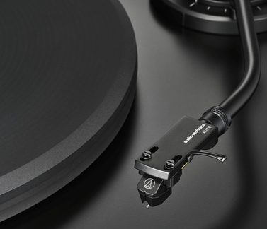 Juodos spalvos Audio-Technica tono centimetrinis planas, sufokusuotas į galvutę ir hi-fi vinilo patefono diską, matinės juodos apdailos