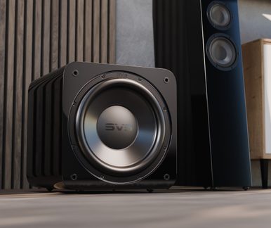 Detailní záběr na lakovaný černý subwoofer SVS s kruhovým reproduktorem, v pozadí ladící hi-fi sloupová reprosoustava
