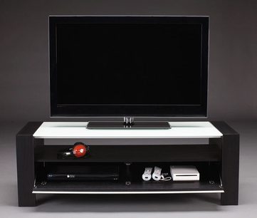 Sort TV-møbel med hvid hylde, DVD-afspiller, spillekonsol og rød fjernbetjening på hylden, fladskærm oven på
