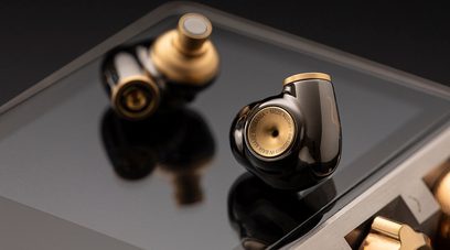 Åbent hi-fi hovedsæt Meze Audio ADVAR i sort og guld, set fra en trekvart bagside vinkel, placeret på en reflekterende grå overflade