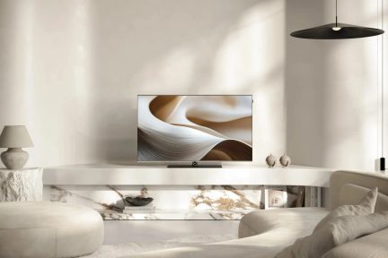 Plochý televizor s minimalistickým designem na bílém televizním stolku v moderním béžovém obývacím pokoji