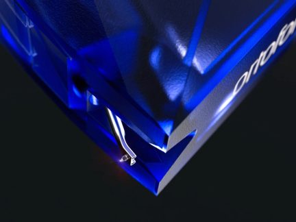 Grootschalig schuin beeld van een fonocelstift, behuizing van gefacetteerd blauw doorzichtig plastic, zichtbare metalen punt