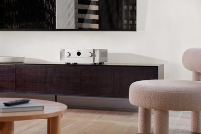 Marantz Cinema 60 DAB -kotiteatterivahvistin hopeisena, etunäkymä olohuoneessa, sijoitettuna tummalle puuhuonekalulle