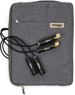 Vista dall’alto di un cavo phono Thorens PhonoConnect PHS 150 XLR-XLR 1,5 m nero con guaina intrecciata, quattro connettori metallici neri con estremità dorate e anelli rosso e argento, appoggiato su una custodia in tessuto grigio antracite con targhetta Thorens