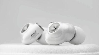Meze Audio Alba -nappikuulokkeet, lähikuva, 2 hopeista kuuloketta, valkoiset silikoniset korvatyynyt, asetettu valkoiselle pinnalle