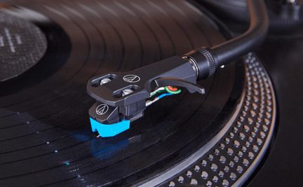 Černé raménko přenosky Audio-Technica s modrou přenoskou na gramofonu v detailním záběru