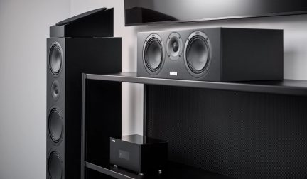 Σετ home cinema Canton σε μαύρο χρώμα με ηχεία δαπέδου, τριών δρόμων κεντρικό ηχείο και ενισχυτή πάνω σε έπιπλο τηλεόρασης
