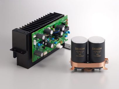 Wzmacniacz hi-fi stereo Denon PMA-2020AE w kolorze srebrnym, z zieloną płytką drukowaną, dwiema dużymi cylindrycznymi czarnymi miedzianymi kondensatorami