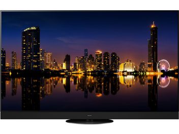 Panasonic TX-65MZ1500E tv-skærm, der viser et natligt fotografi af en oplyst by og dens spejling i vandet