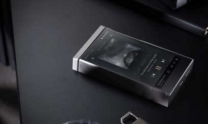 Astell&Kern SE180 sølvfarvet metallic audiofil musikafspiller med tændt skærm, der viser oplysninger, placeret på en sort overflade
