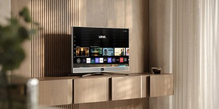 Czarny telewizor Loewe z płaskim ekranem ze srebrnym soundbarem na drewnianym meblu w nowoczesnym salonie