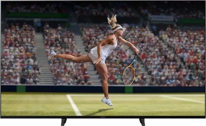 Panasonic TX-49JX940E-fladskærm, der viser en blond kvindelig tennisspiller i hvid dragt, der springer for at slå en tennisbold med sin ketsjer på en græsbane foran en tilskuerskare