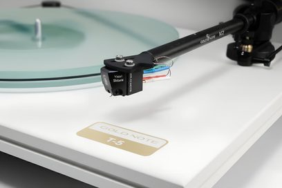 Vit Gold Note T-5 vinylspelare, närbild på svart tonarm och genomskinlig tallrik